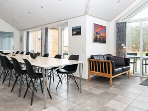 A modern dining area with a large table and chairs, a sofa, and a view of the outdoors. - 5 Star Holiday Home in Romo (Rømø)