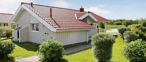 A single-story house with a red-tiled roof, a small porch, and a well-maintained lawn.