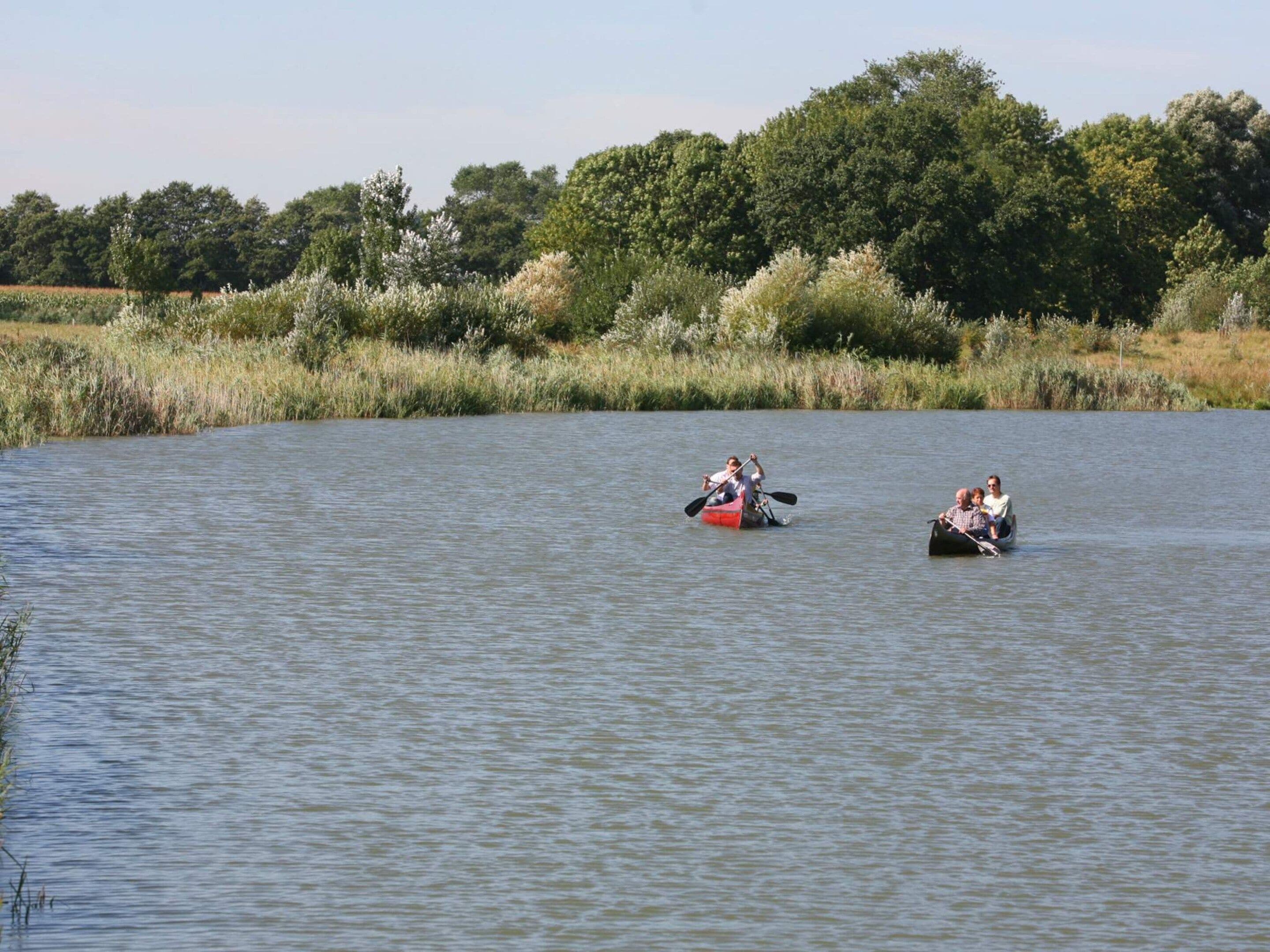 Two canoes on a calm body of water with dense greenery in the background.