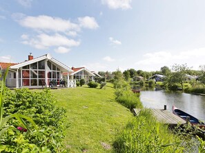 Une propriété située au bord d’un lac, dotée d’une pelouse, d’un quai et d’une rangée de maisons avec de grandes fenêtres.