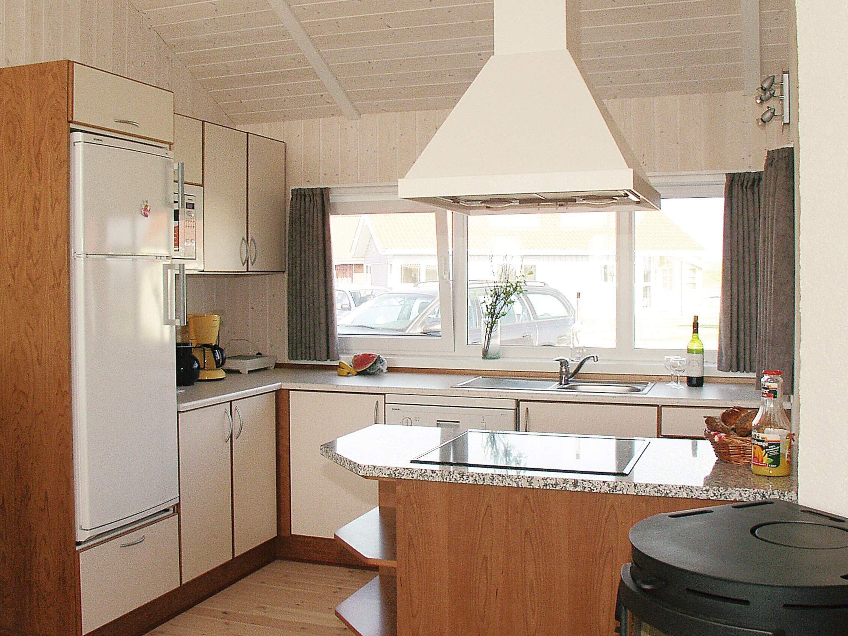 Una cocina compacta con una isla central, microondas integrado y ventana con vistas a la calle.