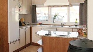 Una cocina compacta con una isla central, microondas integrado y ventana con vistas a la calle.