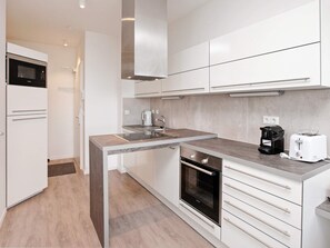 Una cocina moderna con horno empotrado, cafetera y tostadora.