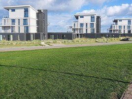 Ein modernes Wohngebäude mit mehreren Wohneinheiten, jeweils mit Balkonen und großen Fenstern.