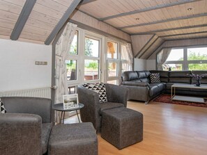 A spacious living room with a high ceiling, large windows, and a sectional sofa.