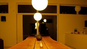 A wooden table with a vase and candle in the center, flanked by two doors leading to a dark room. - 5 Star Holiday Home in Lokken (Lokken)