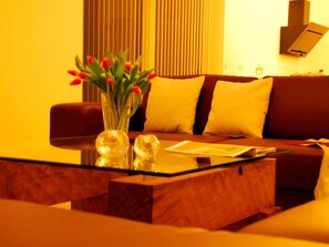 A modern living room with a sofa, a glass coffee table, and a vase with red flowers.