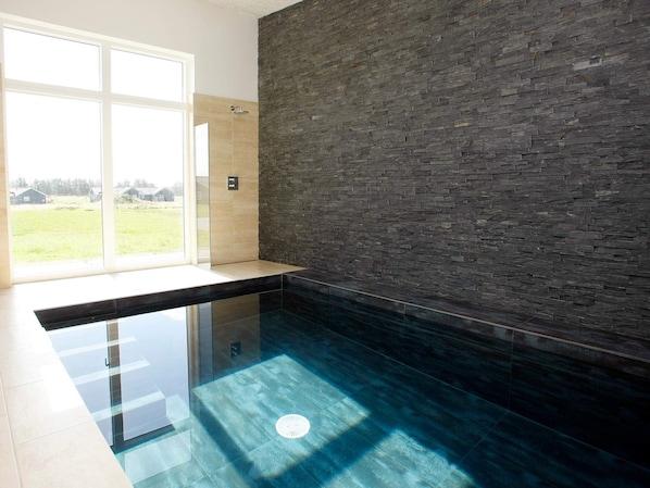 A modern bathroom with a glass-enclosed shower, a stone wall, and a view of the outdoors.