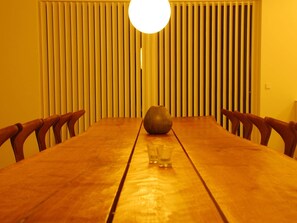 A wooden dining table with chairs, a vase, and a glass of water. - 5 Star Holiday Home in Lokken (Lokken)