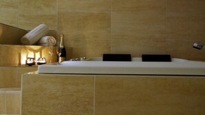 A bathroom with a bathtub, a towel rack with towels, and a bottle of champagne. - 5 Star Holiday Home in Lokken (Lokken)