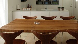 A modern kitchen with a central island, white cabinetry, and stainless steel appliances. - 5 Star Holiday Home in Lokken (Lokken)