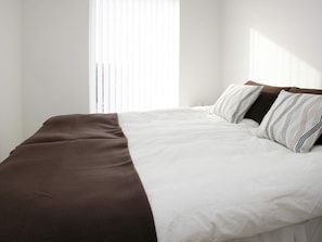 A neatly made bed with a brown and white bedspread and striped pillows.