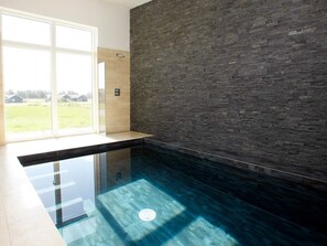 A modern bathroom with a glass-enclosed shower, a dark stone wall, and a view of the outdoors. - 5 Star Holiday Home in Lokken (Lokken)