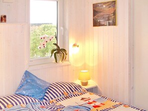 A bedroom with a bed, a window with a view of greenery, a wall-mounted lamp, and a painting. - Holiday Home in GrÃ¶mmitz (Groemitz)