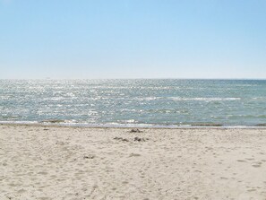 Una playa con arena y el océano al fondo.