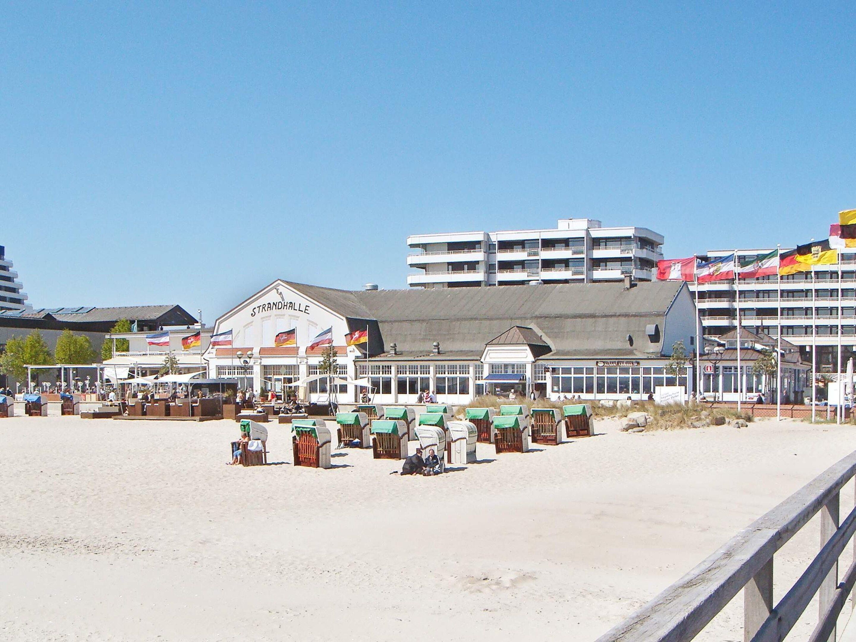 A beachfront hotel with multiple stories, outdoor seating, and flags.