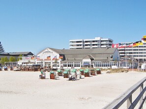 A beachfront hotel with multiple stories, outdoor seating, and flags. - Holiday Home in GrÃ¶mmitz (Groemitz)