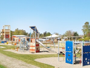 Un parque infantil con diversas estructuras de juego, como un tobogán y escaleras de cuerda.