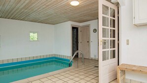 A room with a small pool, a wooden bench, and a door leading to another room. - 9 Person Holiday Home in Blavand (Blavand)