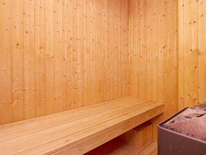 A wooden sauna room with benches and a stone heater. - 9 Person Holiday Home in Blavand (Blavand)