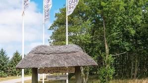 A rustic thatched structure with a sign indicating a restaurant cafe and a distance marker of 600 meters. - 9 Person Holiday Home in Blavand (Blavand)