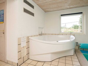 A bathroom with a freestanding bathtub, a window, and a towel rack. - 9 Person Holiday Home in Blavand (Blavand)