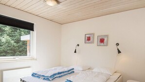 A bedroom with a bed, a window, a bedside table, and two wall-mounted lamps. - 9 Person Holiday Home in Blavand (Blavand)