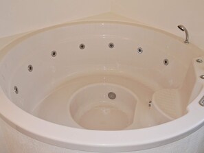 A white hot tub with a curved edge, multiple drain holes, and a built-in seat. - Luxurious Holiday Home in Løkken with Hot Tub & Sauna (Lokken)
