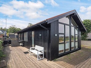 A modern building with large windows, a wooden deck, and a white bench. - 4 Person Holiday Home in Saeby (Sæby)
