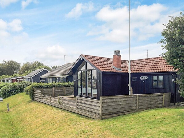 A row of cabins with a wooden deck and a brick chimney. - 4 Person Holiday Home in Saeby (Sæby)