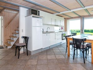 A modern kitchen with white cabinets, a built-in microwave, and a dining area with a table and chairs. - 8 Person Holiday Home in Hemmet (Hemmet)