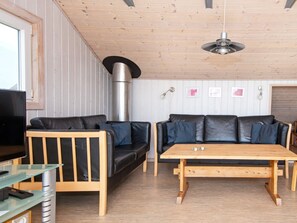 Una sala de estar acogedora con un sofá de cuero negro, una mesa de centro de madera y una chimenea.