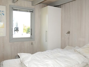 A bedroom with a bed, a wardrobe, and a window.
