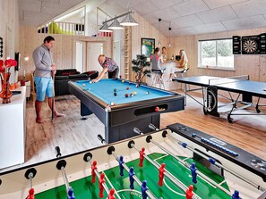 A recreational room with a pool table, foosball table, and a dartboard.
