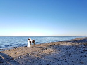 A beach with a horse and a person in white attire.