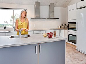 A modern kitchen with a central island, stainless steel appliances, and a view of the outdoors. - Pet Friendly Holiday Home in Bogense with Hot Tub (Bogense)
