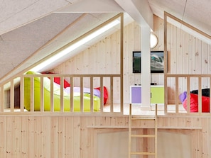 A loft bedroom with a wooden sloped ceiling, a ladder, and a television mounted on the wall. - Pet Friendly Holiday Home in Bogense with Hot Tub (Bogense)