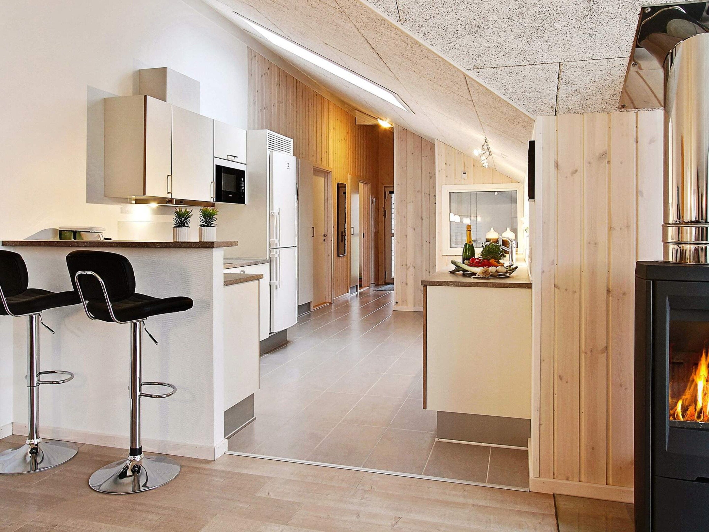 A modern kitchen with a central island, bar stools, a microwave, and a built-in oven.