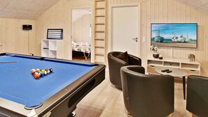 Ein Billardtisch mit Kugeln, ein Sofa, ein Fernseher mit Meerblick und eine Tür zu einem Schlafzimmer.