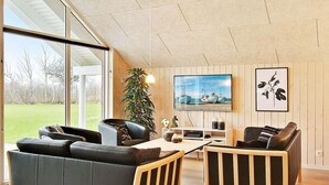 Ein modernes Wohnzimmer mit großem Fenster, Fernseher und einer Pflanze.