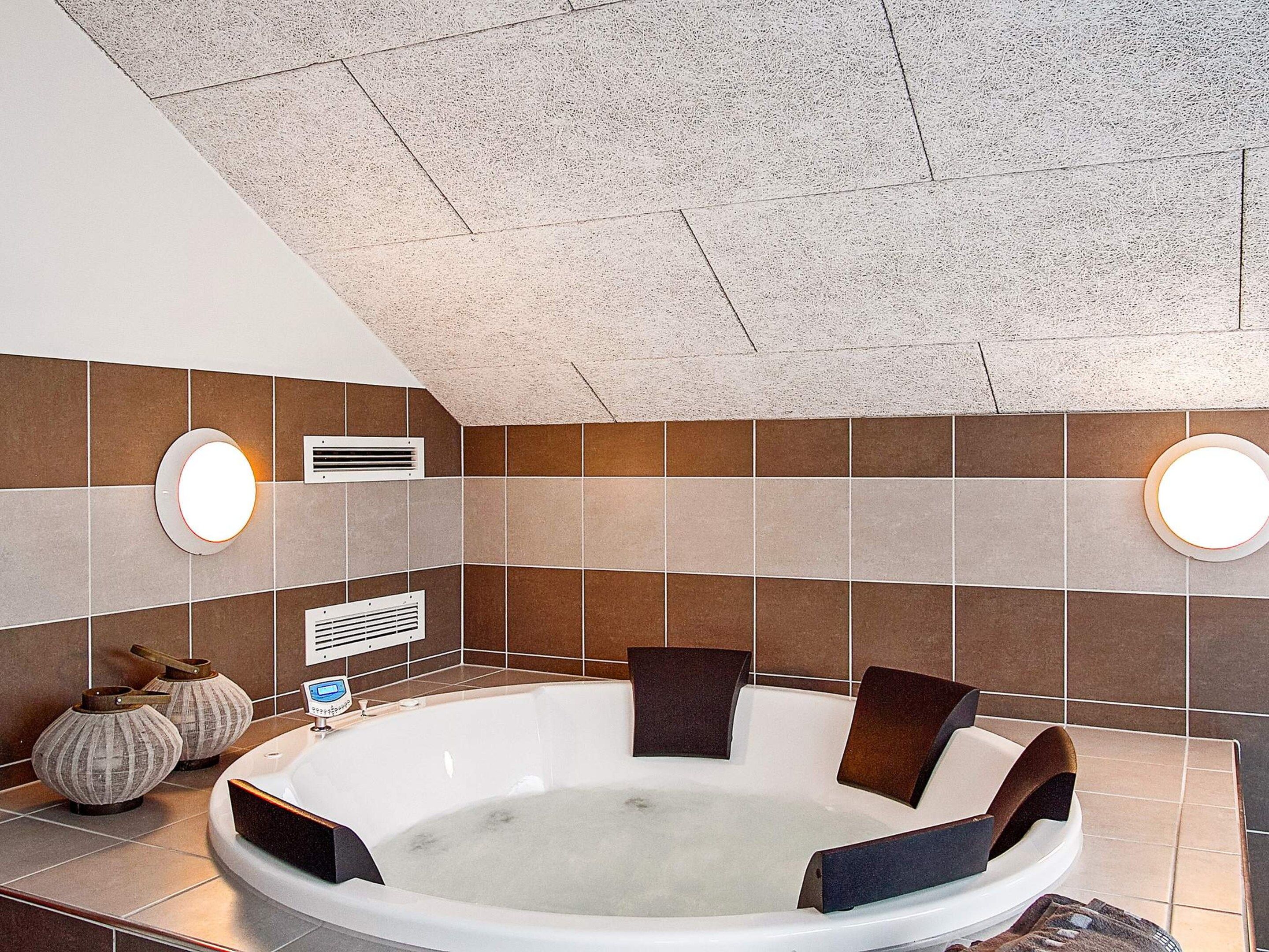 Une salle de bain moderne avec une baignoire sur pieds, deux appliques murales et des vases décoratifs.
