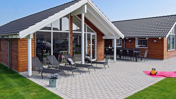 Ein modernes Gebäude mit überdachter Terrasse, Sitzgelegenheiten im Freien und einer sichtbaren Garage.