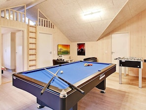 A pool table in a room with wooden walls and a loft area.