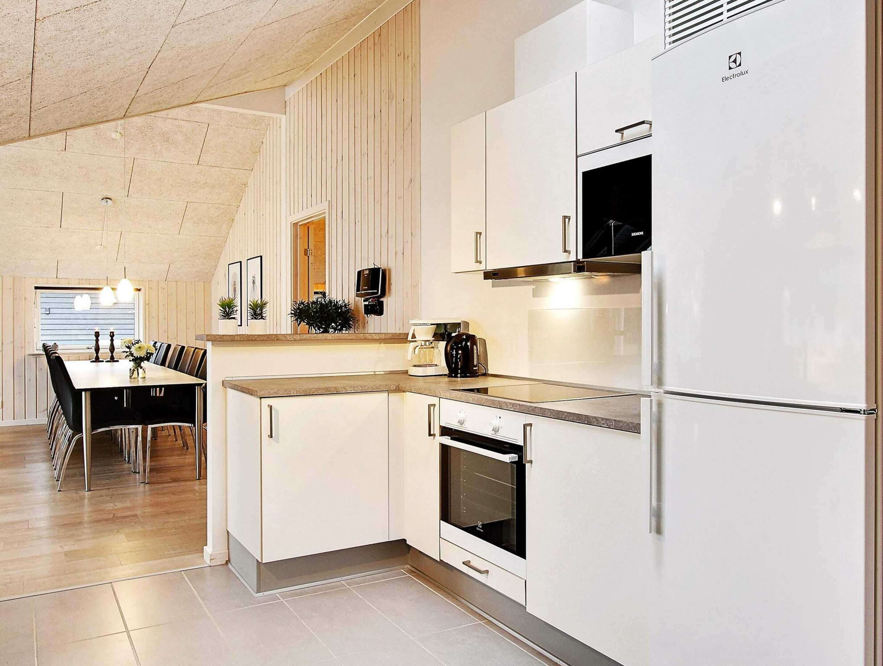 A modern kitchen with white cabinetry, a built-in oven, and a refrigerator.