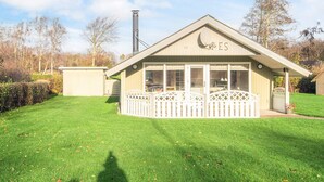 A cozy, single-story building with a sloped roof and a chimney, surrounded by a well-maintained lawn and trees. - Classic Retreat in Bork Havn - By Traum Ferienwohnungen (Hemmet)