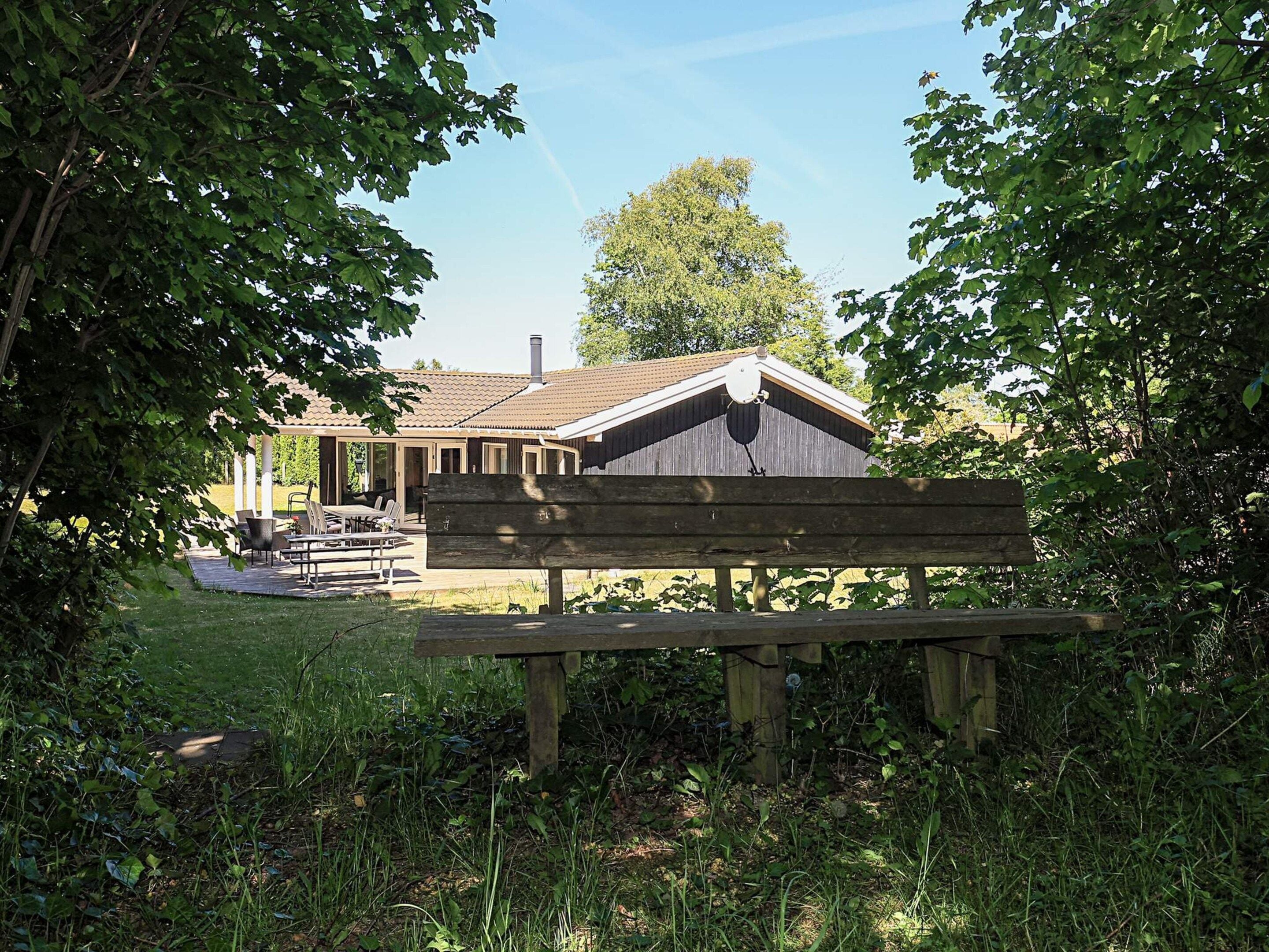 A wooden bench in a garden area with a building in the background.