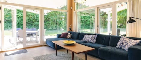 A modern living room with a dark blue sofa, a wooden coffee table, and a patterned rug.