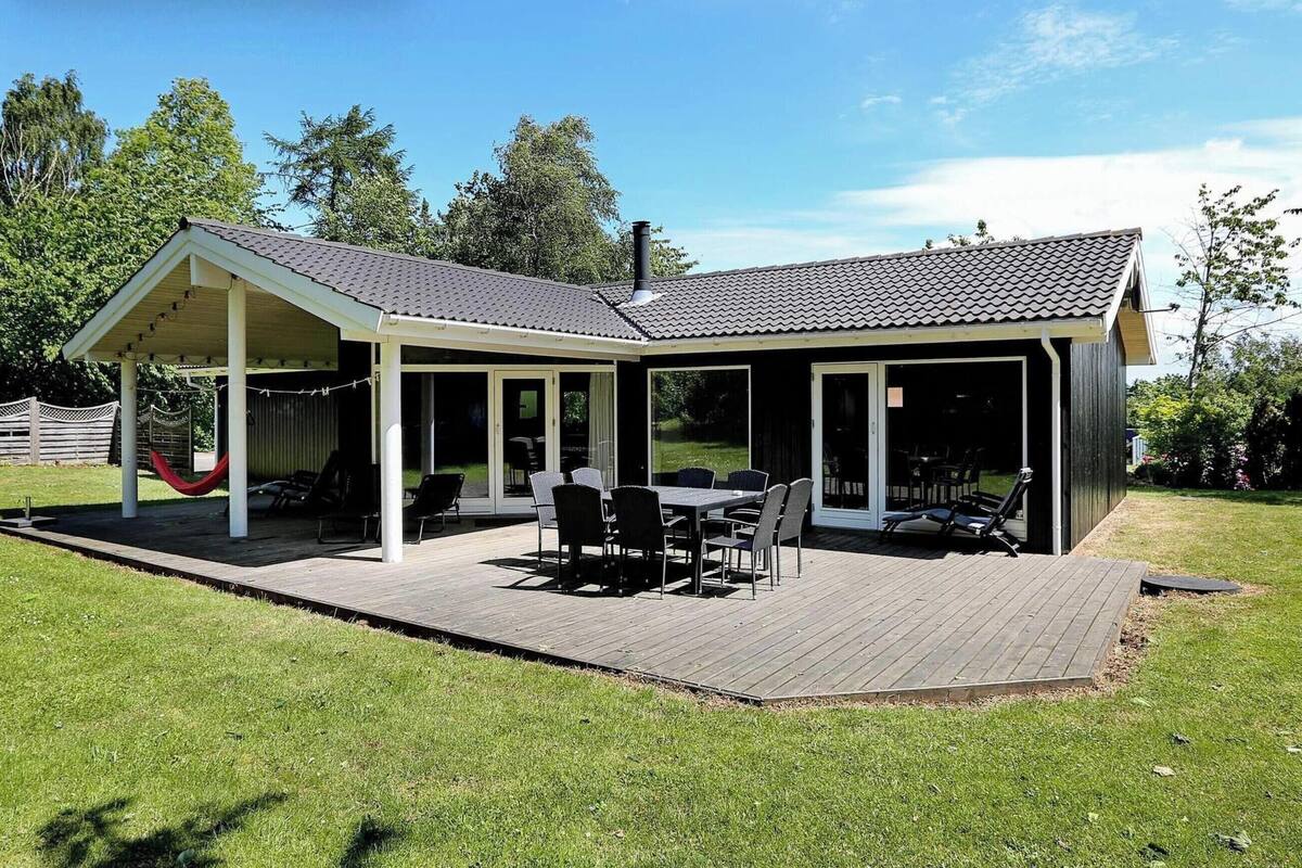 A covered patio with a table and chairs, a hammock, and a fenced area.