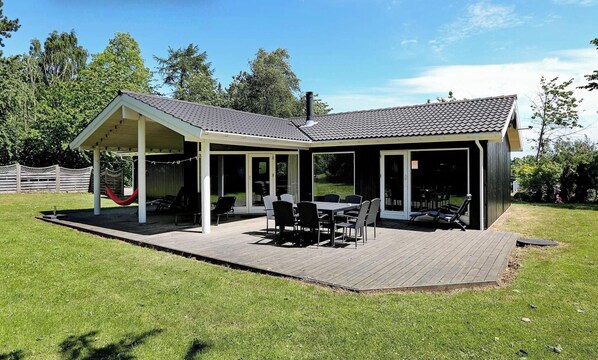 A covered patio with a table and chairs, a hammock, and a fenced area. - 4 Star Holiday Home in Gilleleje (Gilleleje)