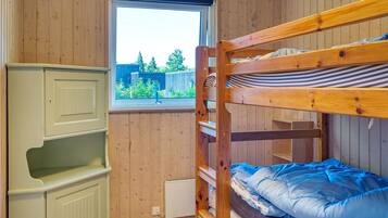 Una cama litera con vistas al exterior, un armario blanco con estantes y una ventana con persianas.